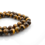 Kesimli Kaplangözü doğal taş dizi 8mm – canlı altın kahverengi yansımalarıyla koruma, cesaret ve denge enerjisi sunan toptan doğal taş dizi