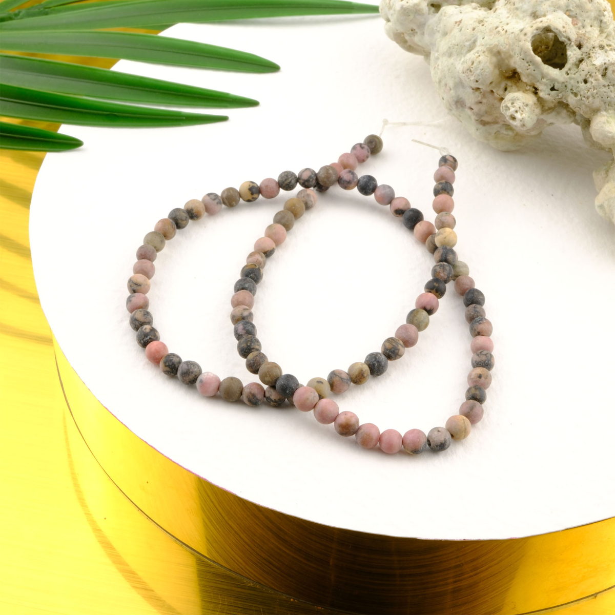 Mat Rodonit 4mm toptan doğal taş dizi – pembe ve siyah tonların uyumuyla sevgi, huzur ve denge enerjisini yansıtan taş; zarif bileklik ve kolye tasarımları için idealdir.