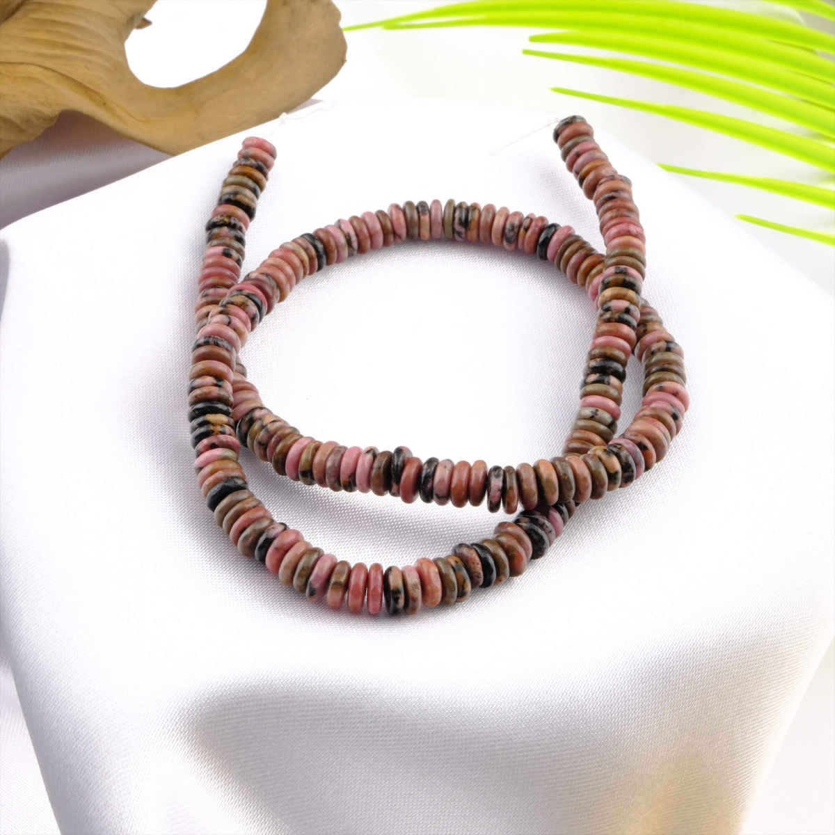 Rondel kesim Rodonit taşı, pembe ve siyah tonlarıyla sevgi, şefkat ve denge enerjisini temsil eden; bileklik, kolye ve tesbih tasarımlarında kullanılan toptan doğal taş dizi.
