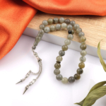 Toptan doğal taş labradorit tesbih, gri zemin üzerinde mavi ve yeşil yansımalarıyla sezgiyi güçlendiren, manevi kullanım ve koleksiyon için ideal doğal taş tesbih