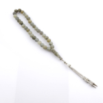 Toptan doğal taş labradorit tesbih, gri zemin üzerinde mavi ve yeşil yansımalarıyla sezgiyi güçlendiren, manevi kullanım ve koleksiyon için ideal doğal taş tesbih