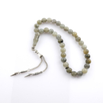 Toptan doğal taş labradorit tesbih, gri zemin üzerinde mavi ve yeşil yansımalarıyla sezgiyi güçlendiren, manevi kullanım ve koleksiyon için ideal doğal taş tesbih