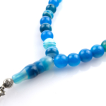 Toptan doğal taş mavi Madagaskar akik tesbih, mavi ve gri tonların doğal damar yapısıyla zihinsel sakinliği destekleyen, manevi kullanım ve koleksiyon için ideal doğal taş tesbih