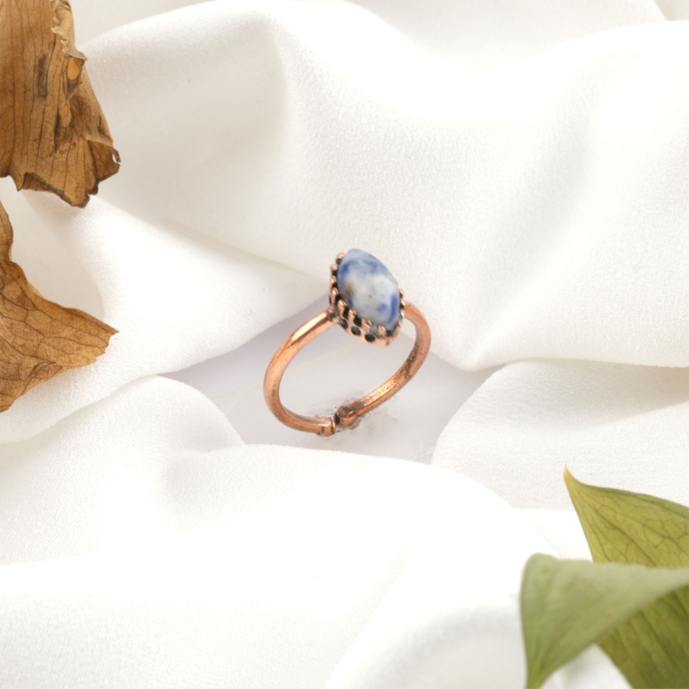 Sodalit doğal taş bakır yüzük, bakırın enerji iletkenliği ve sıcak estetik yapısıyla sodalit taşının lacivert ve beyaz damar geçişli görünümünü bir araya getirir; yüzük formundaki bu şık tasarım, dengeli frekansı ve modern duruşuyla toptan doğal taş yüzük arayanlar için estetik ve enerjiyi birlikte sunar.