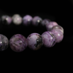 A flexible natural stone bracelet made of round smooth purple veined 5A+ quality charoite beads.