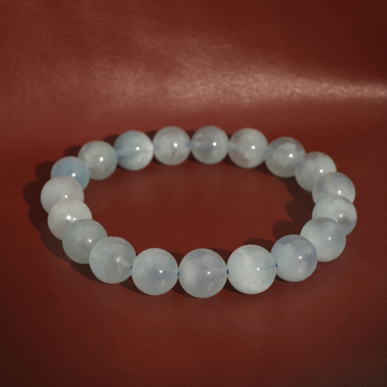 A luxury flexible natural stone bracelet made of 10-11mm round smooth translucent light blue aquamarine beads.