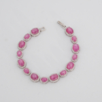 Pulsera elegante de plata de ley 925 para mujer con rubíes rojo-rosado tallados en cabujón y rodeados por marcos ovales de circonitas, exhibida en 1.jpg.