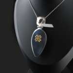 Collana da collezione realizzata a mano in argento sterling 925 con pietra d'ambra naturale originale a forma di goccia, decorata con smalto verde scuro ed eleganti motivi in argento.
