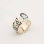 Anillo de hombre de plata 925 con una piedra natural de aguamarina original de talla faceta ovalada y un entorno magistralmente grabado.