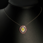 A luxury designer jewelry set including a ring, earrings, and necklace made of original oval cabochon opals surrounded by blue sapphires and pink garnet halos in 925 sterling silver.