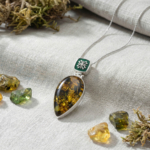 Handgefertigte Sammler-Halskette aus 925er Sterlingsilber mit einem tropfenförmigen originalen Naturbernstein, verziert mit dunkelgrüner Emaillearbeit und eleganten Silbermotiven.