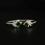 A luxury designer bangle bracelet featuring original faceted square green tourmaline gemstones adorned with marquise zircon flowers in 925 sterling silver.