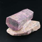 Original raw ruby natural stone piece in pink and red tones resting on a natural matrix.