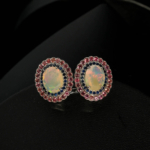 Merkezinde oval kabaşon opal, çevresinde faset kesim lacivert safir ve pembe garnet taşları barındıran 925 ayar gümüş tasarım yüzük, küpe ve kolye ucu seti modeli.