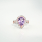 A luxury women's statement ring featuring a pear-cut original amethyst gemstone surrounded by pink and white cubic zirconia with rose gold plating in 925 sterling silver.