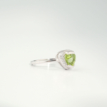 A delicate women's statement ring featuring a trillion-cut original peridot gemstone surrounded by cubic zirconia in 925 sterling silver.