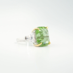 A luxury statement women's ring featuring a massive 16.17ct radiant-cut original rutilated peridot gemstone flanked by trapezoid cubic zirconia in 925 sterling silver.