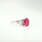 A delicate women's statement ring featuring an oval-cut original ruby gemstone flanked by cubic zirconia in 925 sterling silver.