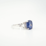 A delicate women's statement ring featuring an oval-cut original blue sapphire gemstone flanked by cubic zirconia in 925 sterling silver.