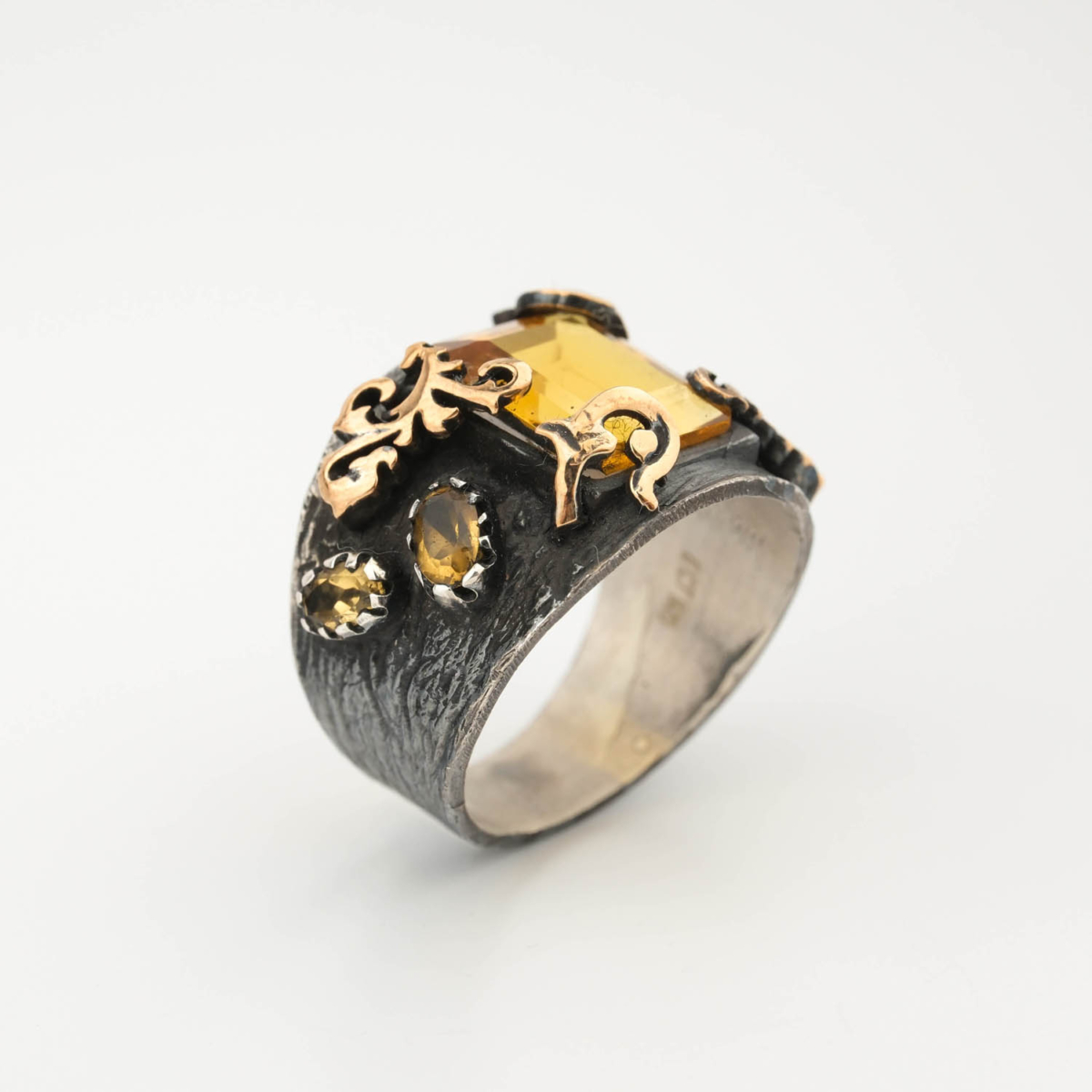 A luxury men's handcrafted statement ring featuring an original emerald cut yellow citrine gemstone set in a shield design on a textured 925 sterling silver band with gold accents.
