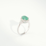 A delicate women's statement ring featuring an oval-cut original emerald gemstone surrounded by cubic zirconia halo in 925 sterling silver.