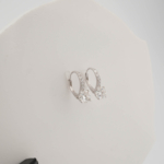 A luxury pair of solitaire hoop earrings featuring certified D color VVS1 round brilliant moissanite gemstones set in 925 sterling silver with a GRA certificate.