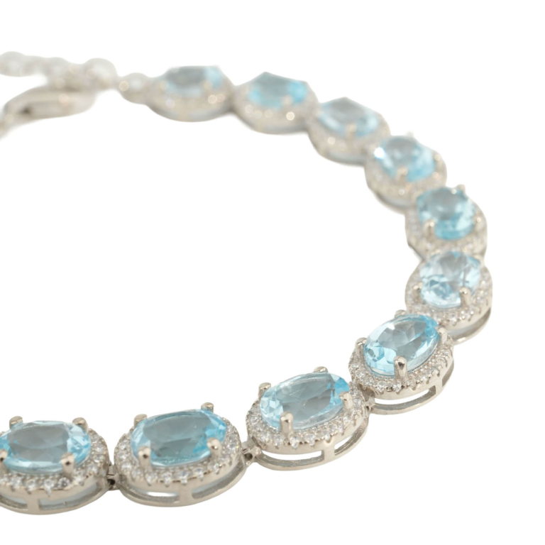 A luxury gemstone bracelet featuring original oval faceted blue topaz crystals set in a 925 sterling silver halo design.
