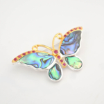 A luxury multi-functional designer brooch and necklace featuring original abalone mother of pearl and faceted red ruby gemstones in a 925 sterling silver butterfly design.