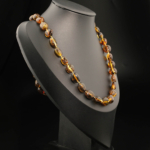 A certified original Baltic amber gemstone adult necklace (23-28g, 60-65cm) featuring smooth dark cognac amber beads with golden mica inclusions.