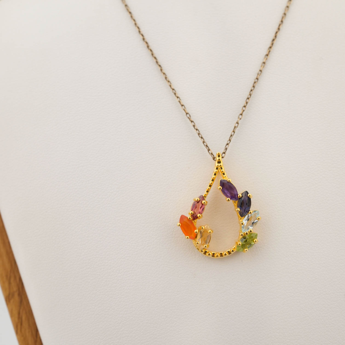 A luxury multi-gemstone designer pendant featuring marquise cut agate, citrine, tourmaline, peridot, topaz, sapphire, and amethyst in gold plated 925 silver.