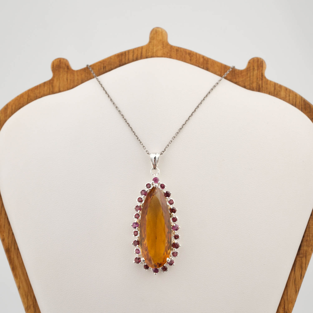 A luxury designer necklace featuring an original marquise faceted citrine surrounded by a pink tourmaline halo in 925 sterling silver.