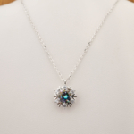 A luxury designer necklace featuring a certified round faceted mystic topaz set in a 925 sterling silver snowflake pendant.