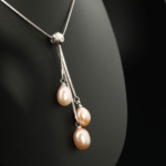 Ciondolo di design di lusso in acciaio inossidabile con tre perle naturali dell'oceano rosa a forma di goccia.
