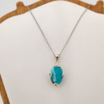 Colgante de diseño de lujo en plata de ley 925, adornado con una piedra turquesa natural ovalada de corte cabochon.