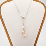 Colgante de diseño de lujo en acero inoxidable con tres perlas naturales de océano rosadas en forma de gota.