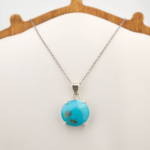 Colgante de diseño de lujo en plata de ley 925, adornado con una gemma turquesa natural de corte cabochon.