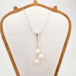 Colgante de diseño de lujo en acero inoxidable con tres perlas naturales de océano blancas en forma de gota.