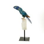 A luxury hand-carved gemstone parrot sculpture made of sodalite, blue calcite, and clear quartz on a black metal stand.