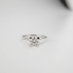 A luxury solitaire designer ring featuring a certified 1.2 carat D color VVS1 round brilliant moissanite gemstone set in a four-prong 925 sterling silver plain band with a GRA certificate.