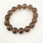 A stylish gemstone statement bracelet featuring original 14-15mm 6A+ grade smoky quartz round beads on a stretch band.