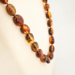A certified original Baltic amber gemstone adult necklace (25-30g, 60-65cm) featuring smooth large cognac amber beads.