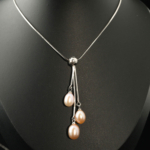 Pendentif de luxe en acier inoxydable orné de trois perles de culture d'océan roses en forme de goutte.