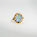 A gold-plated 925 sterling silver women's ring featuring a natural oval cabochon blue aquamarine gemstone with twisted rope bezel and band.