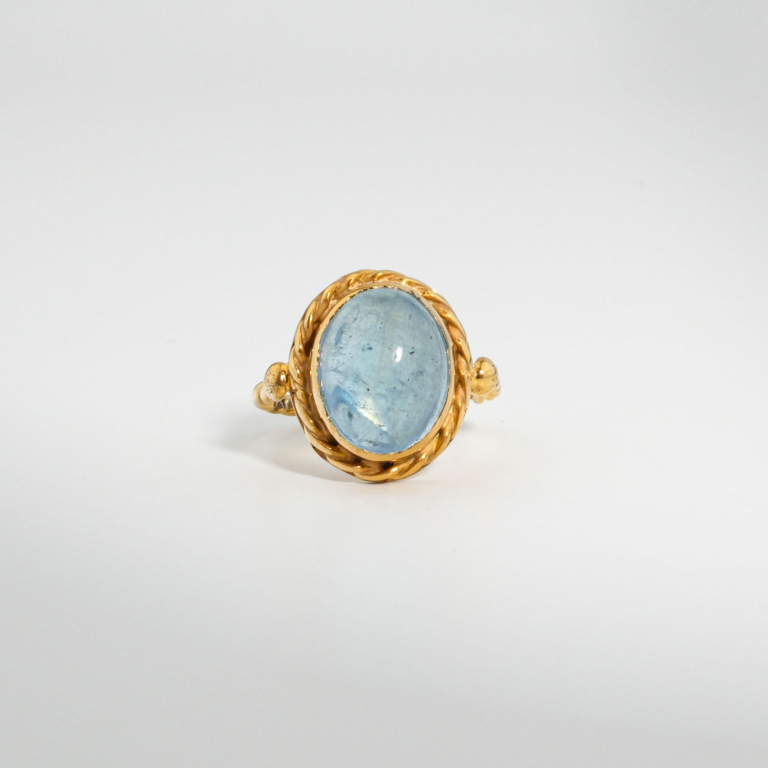 A gold-plated 925 sterling silver women's ring featuring a natural oval cabochon blue aquamarine gemstone with twisted rope bezel and band.