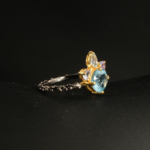 A 925 sterling silver women's crown design ring featuring a natural round blue topaz gemstone accented with sapphire stones.