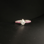 A 925 sterling silver women's ring featuring a natural pear-shaped clear rock crystal gemstone accented with round ruby side stones.
