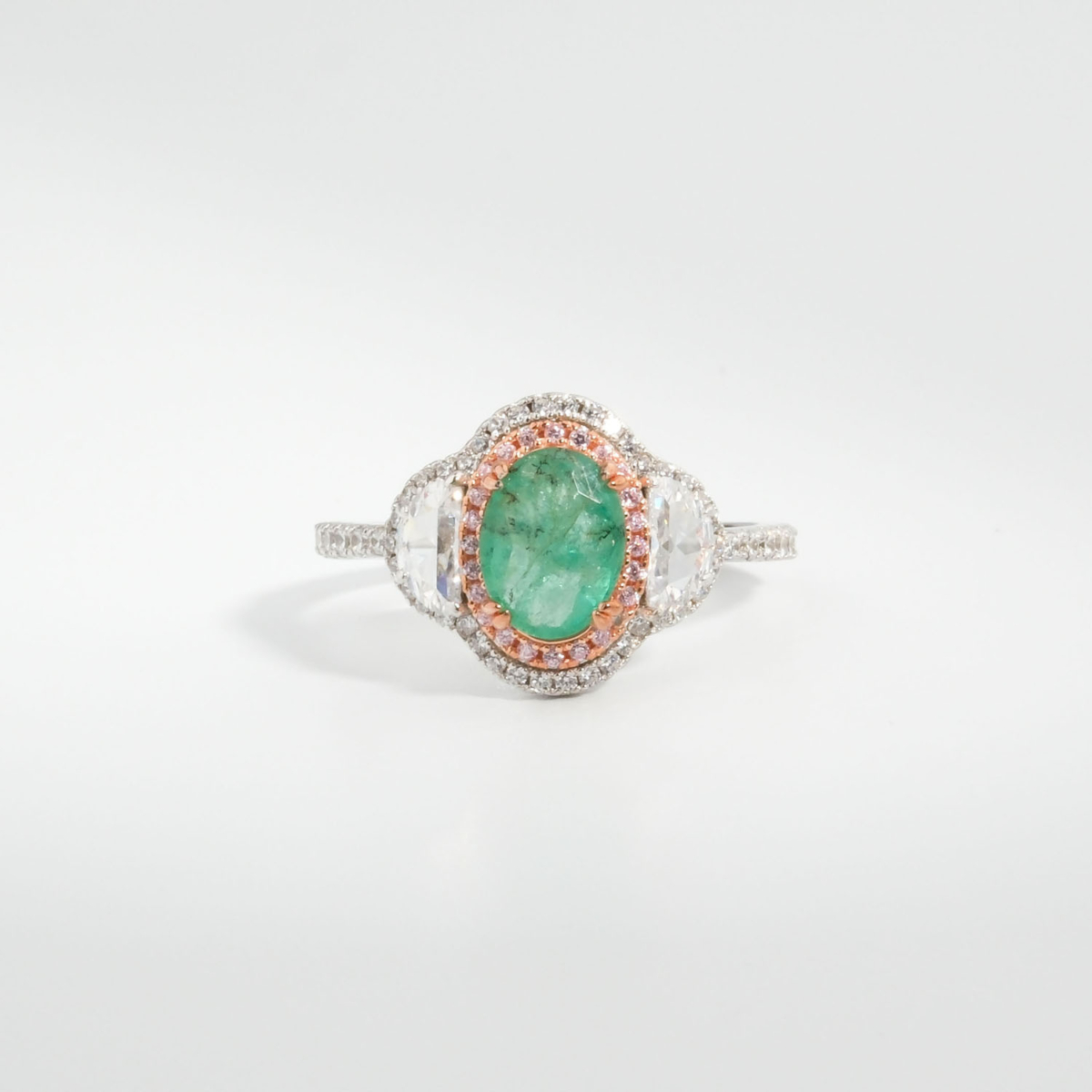 A 925 sterling silver women's ring featuring a 1.24 ct natural oval green Zambian emerald gemstone with pink and white cubic zirconia halo.