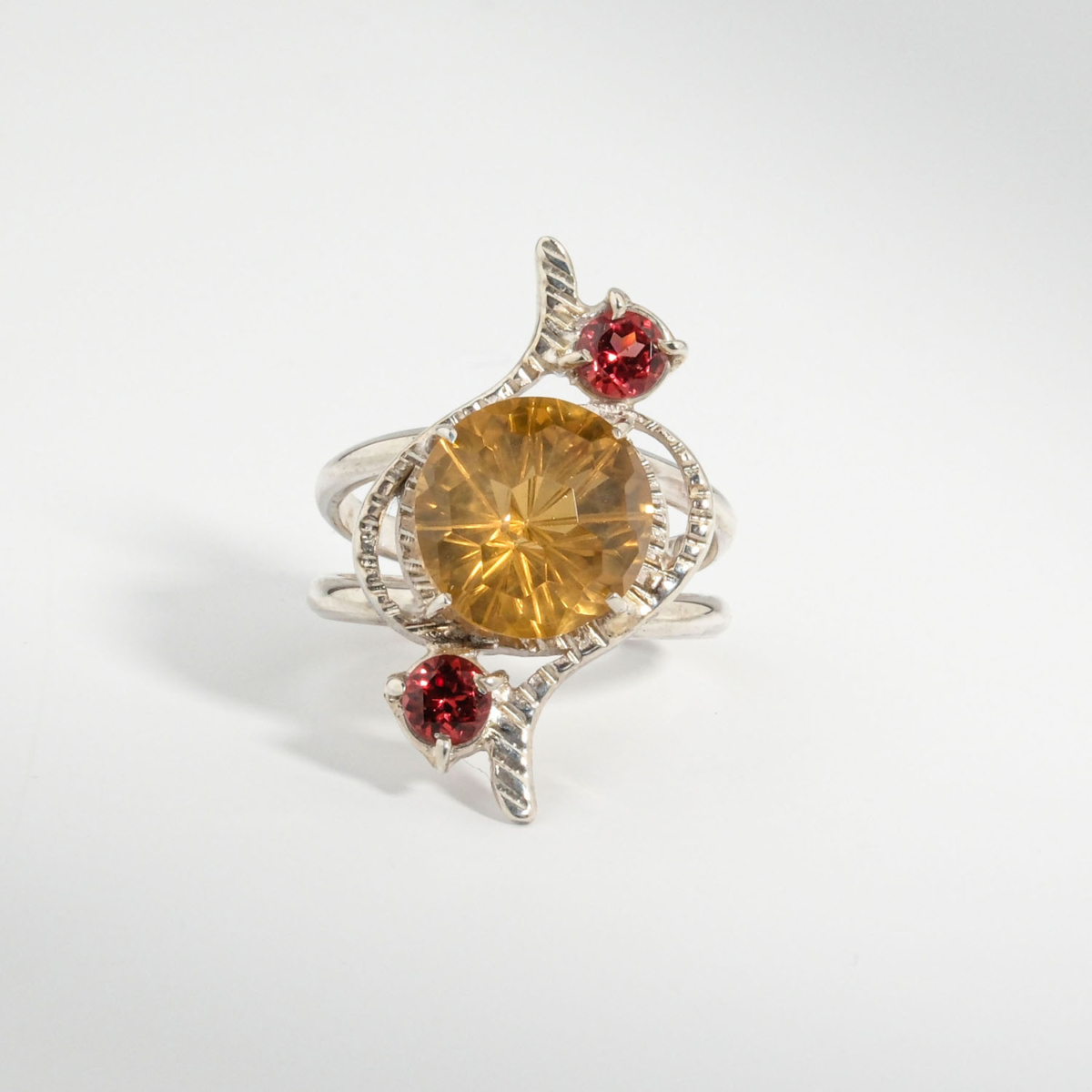 A 925 sterling silver handmade women's ring featuring a round faceted yellow citrine gemstone accented with two red garnets.
