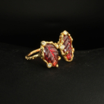 A 925 sterling silver gold-plated women's bypass ring featuring hand-carved garnet leaf gemstones accented with small cubic zirconia / blue topaz stones.