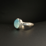 A 925 sterling silver women's ring featuring a natural oval cabochon blue quartz gemstone in a smooth bezel setting.